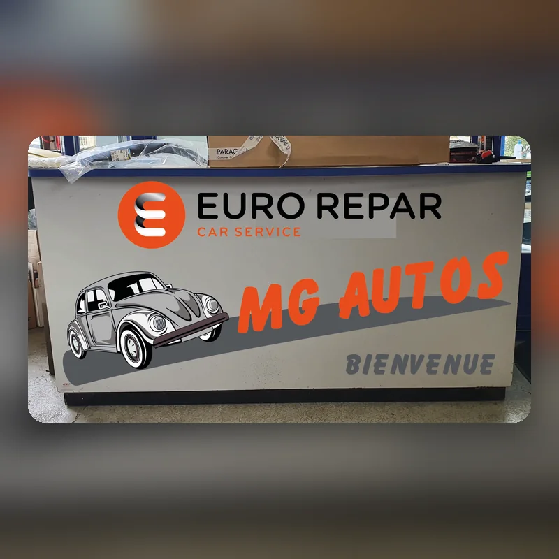 Banque d’accueil habillée d’un panneau gris : logo Eurorepar Car Service, Coccinelle et « MG Autos, Bienvenue »