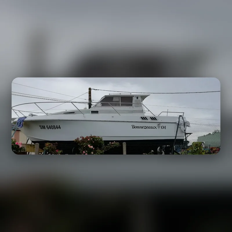 Bateau de plaisance blanc sur son ber, nom « Bonnezeaux 04 » et immatriculation en adhésif sur la coque