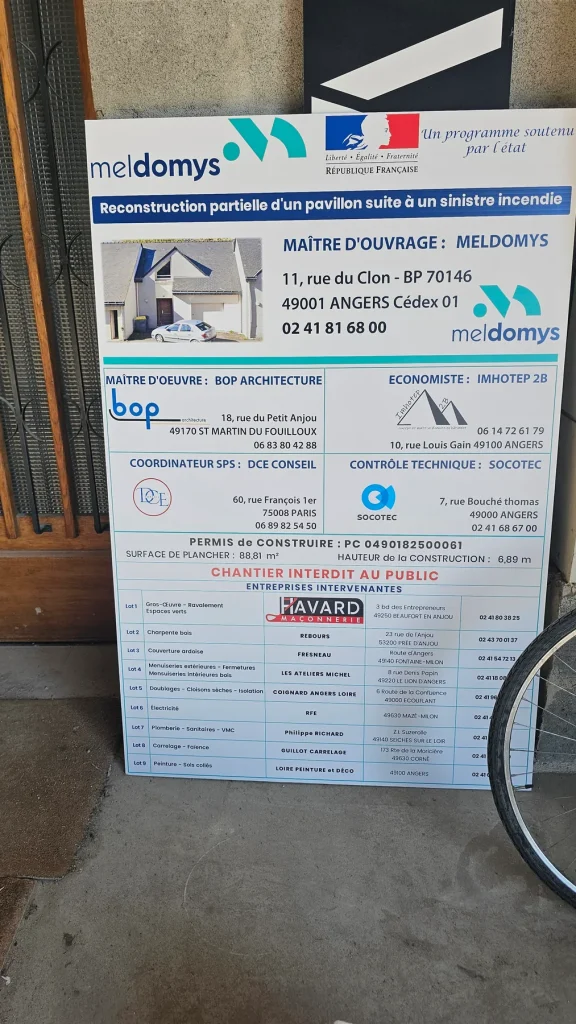 Panneau de chantier blanc et bleu : reconstruction d’un pavillon, maître d’ouvrage et entreprises intervenantes