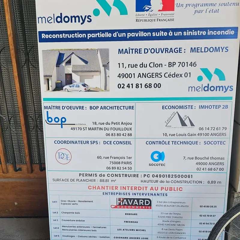 Panneau de chantier blanc et bleu : reconstruction d’un pavillon, maître d’ouvrage et entreprises intervenantes