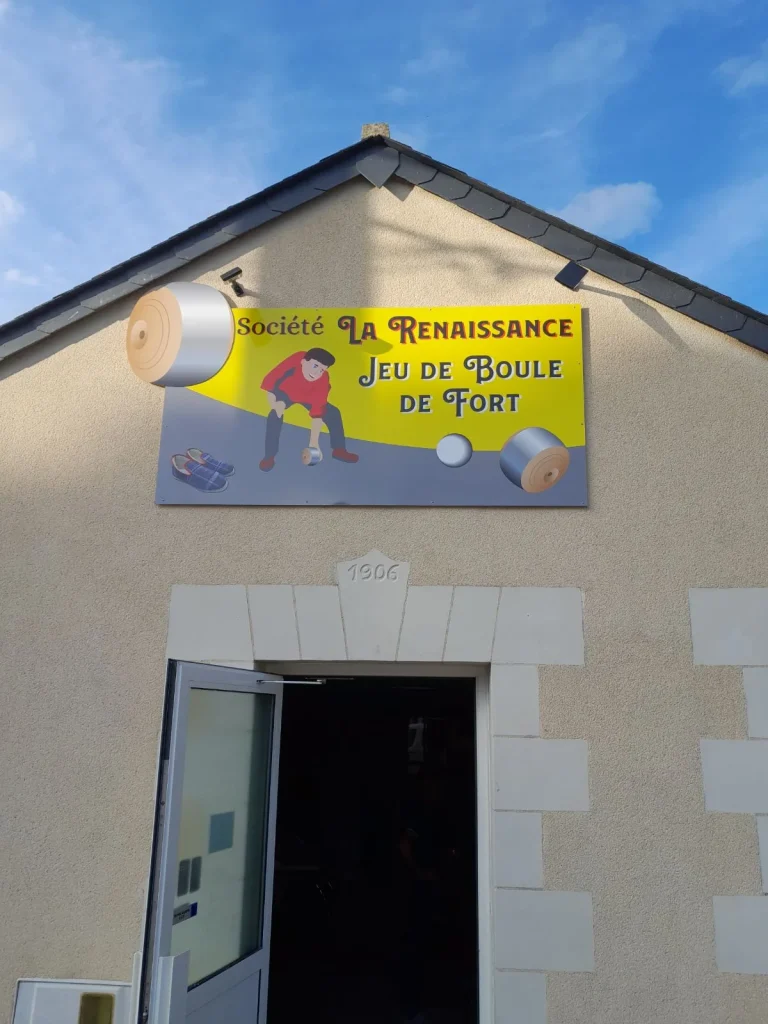 Enseigne jaune de la Société La Renaissance, jeu de boule de fort, au-dessus de la porte d’un bâtiment en tuffeau