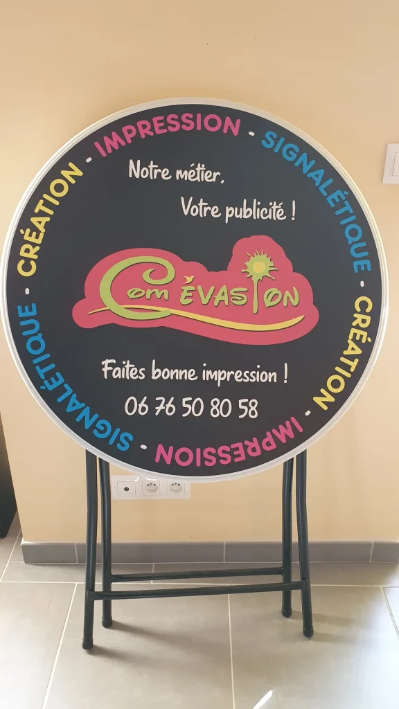 Mange-debout noir au logo Com Évasion, entouré des mots Impression, Signalétique et Création