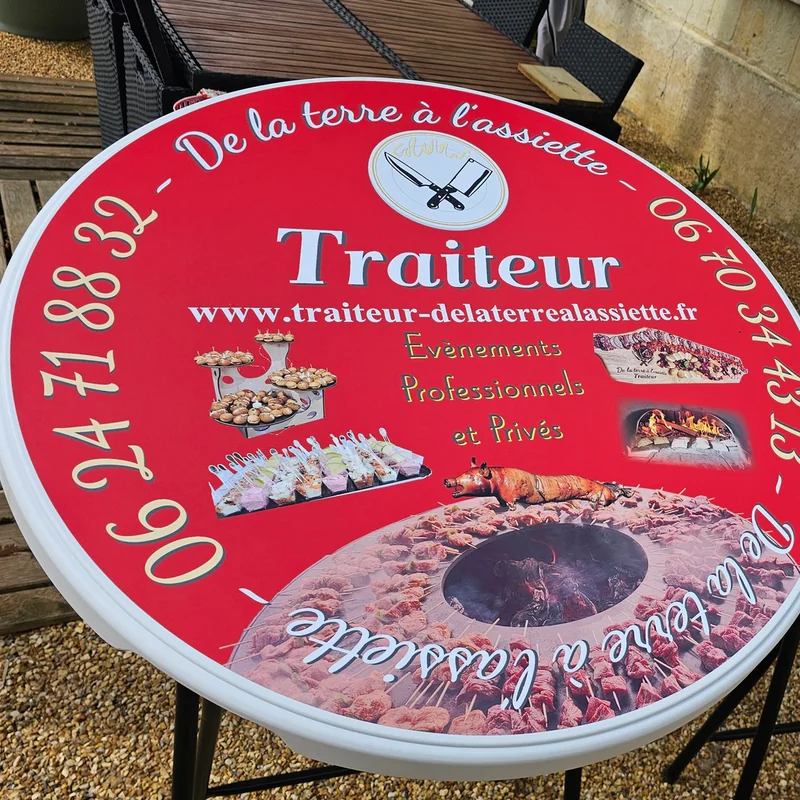 Deux mange-debout rouges « De la terre à l’assiette, Traiteur » avec photos de plats