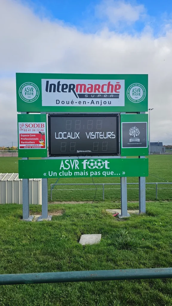 Tableau d’affichage du stade de l’ASVR Foot, habillé en vert avec le logo du club et les partenaires