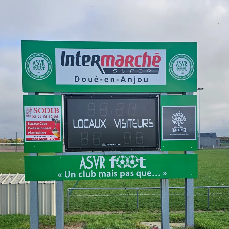 Tableau d’affichage du stade de l’ASVR Foot, habillé en vert avec le logo du club et les partenaires