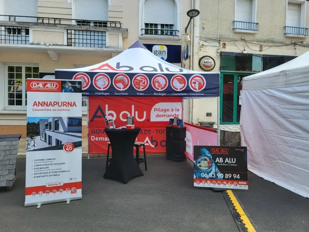 Stand extérieur AB Alu : tente pliante bleu et rouge, roll-up Dal’Alu et panneau sur une place