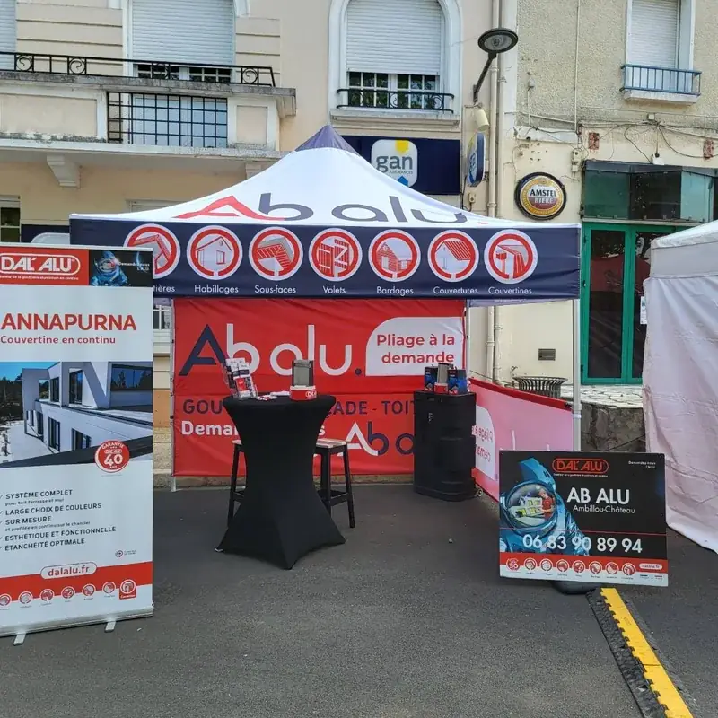 Stand extérieur AB Alu : tente pliante bleu et rouge, roll-up Dal’Alu et panneau sur une place