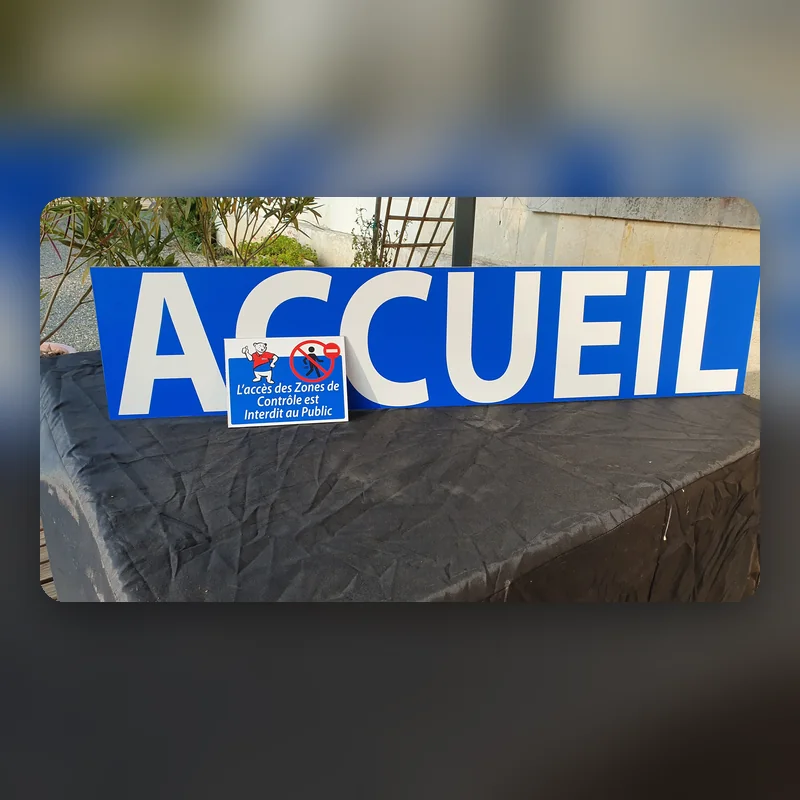 Grand panneau bleu « Accueil » en lettres blanches avec une plaque d’interdiction au public