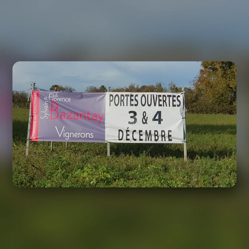 Banderole « Sylvain et Florence Bazantay, vignerons, portes ouvertes 3 et 4 décembre » tendue au bord d’un champ