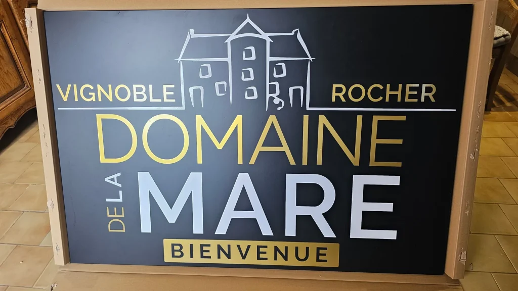 Panneau noir « Vignoble Rocher, Domaine de la Mare, Bienvenue » en lettres dorées et blanches
