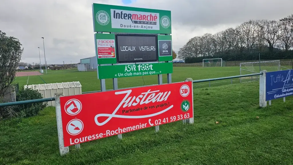 Panneau rouge Justeau, partenaire de vos projets, en bord de terrain de football sous le tableau de l’ASVR
