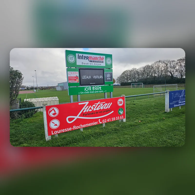 Panneau rouge Justeau, partenaire de vos projets, en bord de terrain de football sous le tableau de l’ASVR
