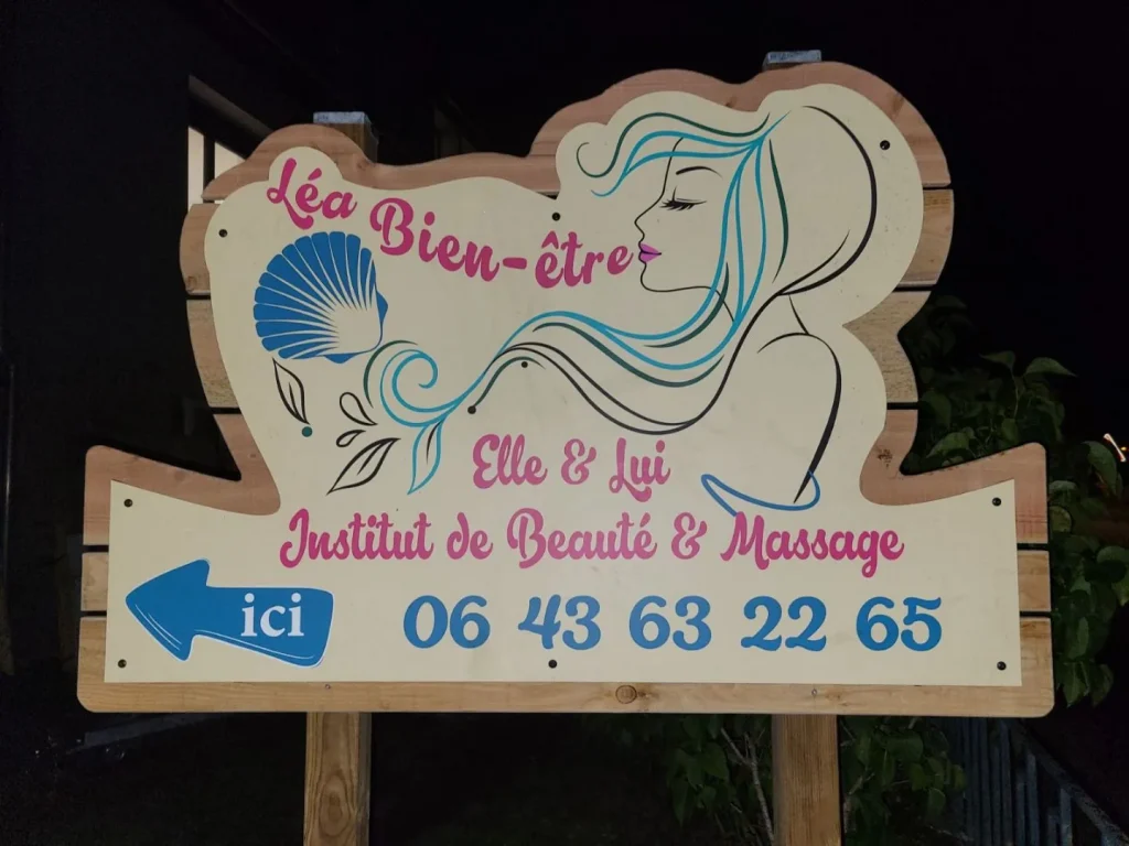 Panneau découpé à la forme du logo Léa Bien-être, avec une flèche « ici » et le numéro, sur poteaux de bois