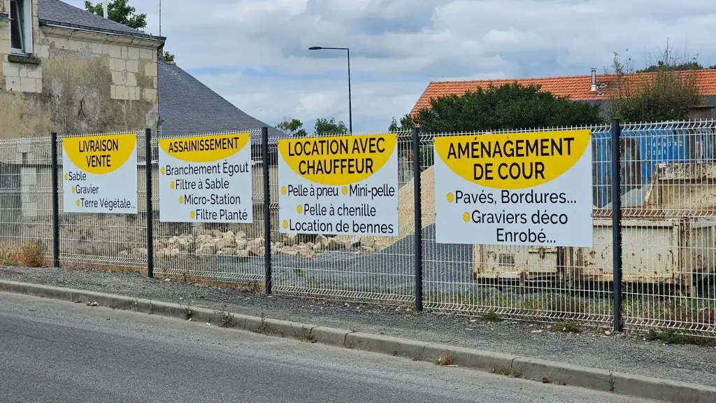 Quatre panneaux jaunes Hudon TP fixés sur une clôture le long d’une route