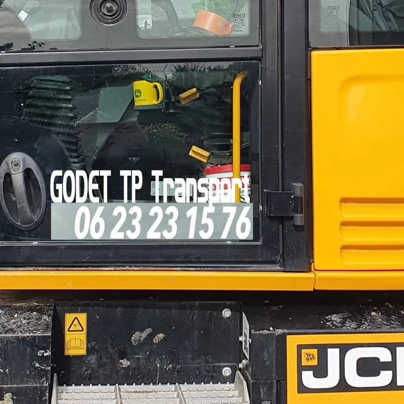 Pelle JCB jaune avec le lettrage « Godet TP Transport » et le numéro sur la vitre de la cabine