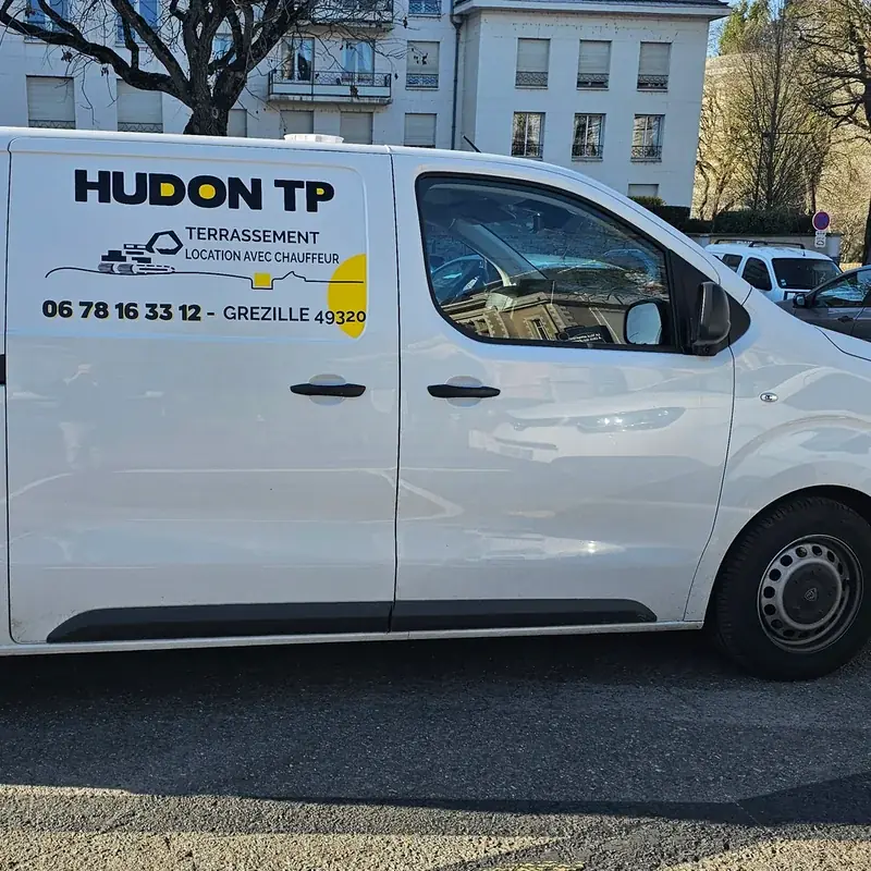 Utilitaire blanc marqué au logo Hudon TP, terrassement, sur la portière arrière